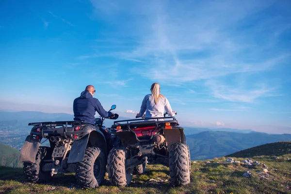 Achteraanzicht van jonge paar in de buurt van atv. Man is iets aan haar vriendin in de afstand tonen. — Stockfoto