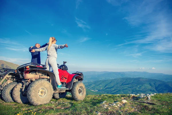 Güzel çift üzerinden atv quadbike üzerinde oturan dağ gün batımını izlemek — Stok fotoğraf