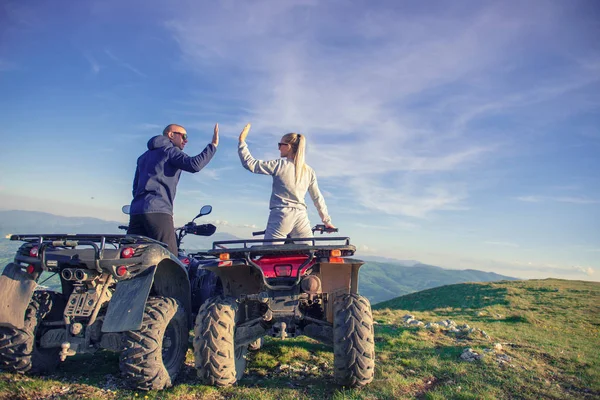 Rear view of young pair near atv. Man is showing something in distance to her girlfriend. — Stock Photo, Image