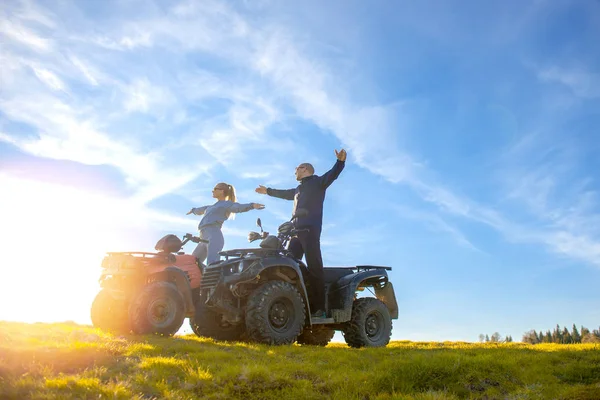 美しいカップルは atv quadbike の上に座って山から夕日を見ています。 — ストック写真