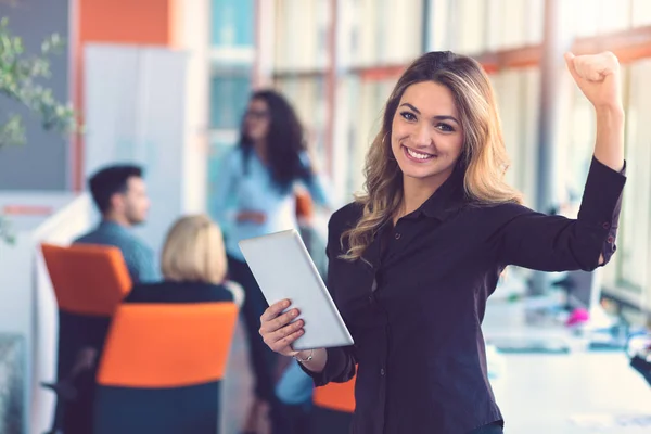 Portrait of happy business woman holding digital tablet in office standing in front of koleges discussing at background Stok Foto Bebas Royalti