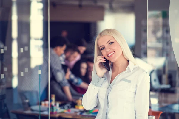 Mosolygó üzletasszony telefonál, miközben az irodában áll — Stock Fotó