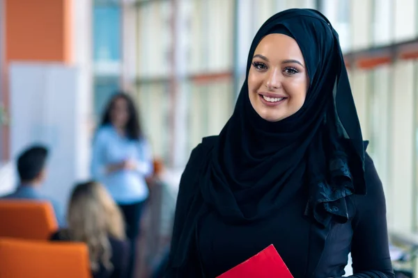 Cheerful woman in the office, holding folder with documents and giving a bright smile. Muslim women employment. — Stock Photo, Image