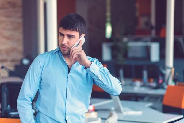 Joven hombre de negocios sonriente llamando por teléfono en la oficina . —  Fotos de Stock