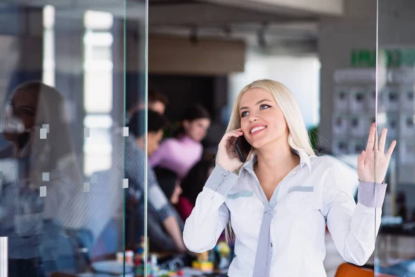 Usmívající se podnikatelka pomocí telefonu, když stojí v úřadu — Stock fotografie