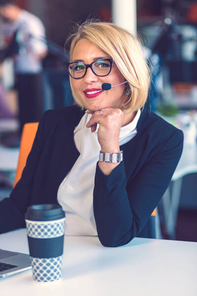 Представитель по работе с клиентами. Красивая молодая женщина в наушниках работает за компьютером
