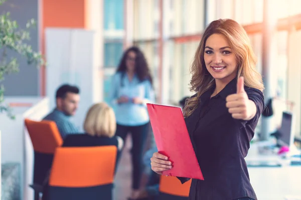 Donna d'affari con cartelle in piedi e compagni di squadra che lavorano in sala riunioni in ufficio . — Foto Stock