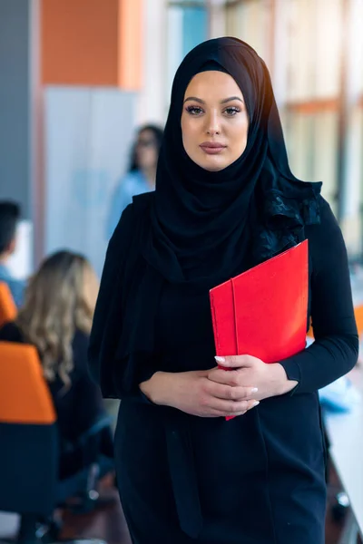 Femme gaie dans le bureau, tenant un dossier avec des documents et donnant un sourire lumineux. Femmes musulmanes emploi . — Photo