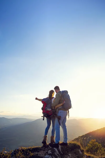 Vandrare med ryggsäckar koppla av på toppen av ett berg och njuta av utsikten över dalen — Stockfoto