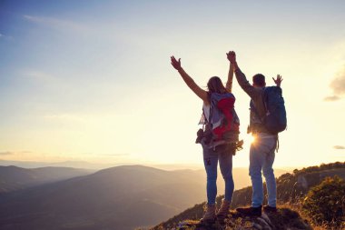 Mutlu çift, yaz yürüyüşü sırasında gün batımında dağın tepesinde gezen turist.
