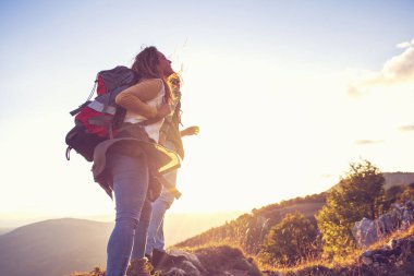 Sırt çantalı yürüyüşçüler bir dağın tepesinde dinleniyorlar ve vadinin manzarasının tadını çıkarıyorlar.