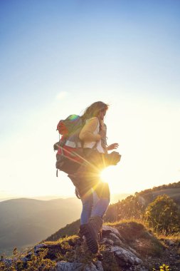 Sırt çantalı yürüyüşçüler bir dağın tepesinde dinleniyorlar ve vadinin manzarasının tadını çıkarıyorlar.