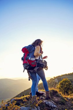 Sırt çantalı yürüyüşçüler bir dağın tepesinde dinleniyorlar ve vadinin manzarasının tadını çıkarıyorlar.