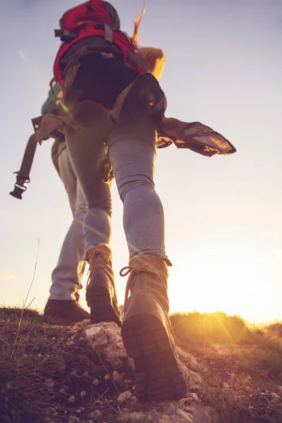 Tourist couple wearing hiking boots walk up a grassy hill in Alps. — Stock Photo, Image