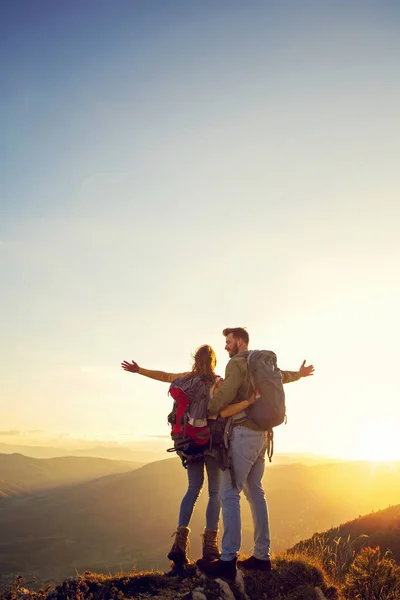 Hikers with backpacks relaxing on top of a mountain and enjoying the view of valley — Stock Photo, Image