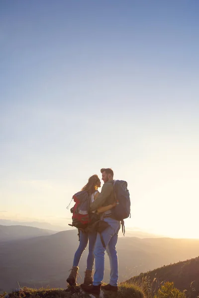 Hikers with backpacks relaxing on top of a mountain and enjoying the view of valley — Stock Photo, Image