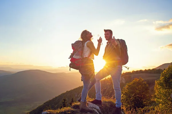 Casal jovem caminhando no pico da água potável da montanha — Fotografia de Stock