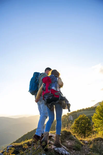 Wandelaars met rugzakken ontspannen op de top van een berg en genieten van het uitzicht op de vallei — Stockfoto