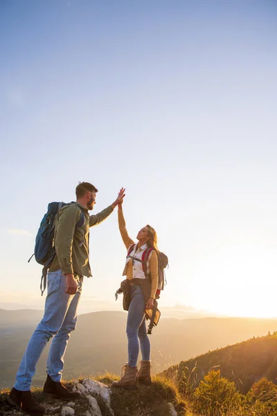 Couple au sommet d'une montagne serrant les mains levées — Photo