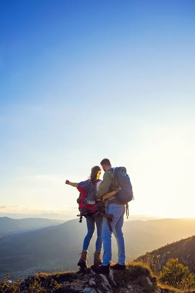 Hikers with backpacks relaxing on top of a mountain and enjoying the view of valley — Stock Photo, Image