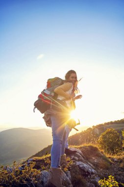Sırt çantalı yürüyüşçüler bir dağın tepesinde dinleniyorlar ve vadinin manzarasının tadını çıkarıyorlar.