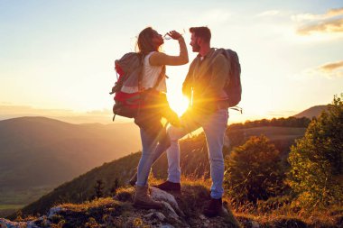 Genç çift dağın zirvesinde yürüyüş yapıyor içme suyu içiyor.