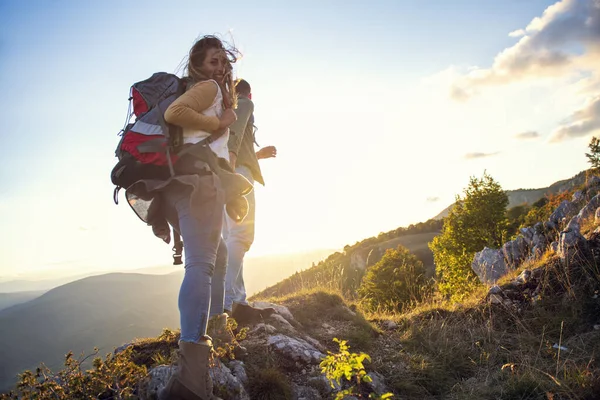 Hikers with backpacks relaxing on top of a mountain and enjoying the view of valley — Stock Photo, Image