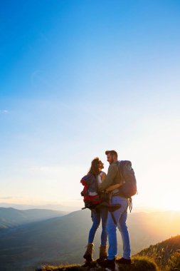 Sırt çantalı yürüyüşçüler bir dağın tepesinde dinleniyorlar ve vadinin manzarasının tadını çıkarıyorlar.