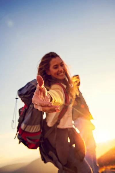 People helping each other hike up a mountain at sunrise. — Stock Photo, Image