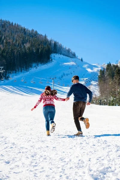 Luta de bolas de neve. Casal de inverno se divertindo jogando na neve ao ar livre. Jovem alegre feliz casal multi-racial . — Fotografia de Stock