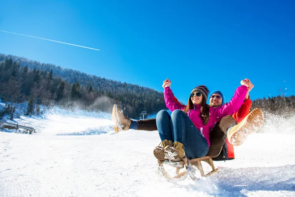 Jong gelukkig paar sleeën in de winter in het skicentrum — Stockfoto