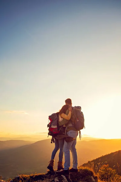 Туристи з рюкзаками відпочивають на вершині гори і насолоджуються видом на долину — стокове фото