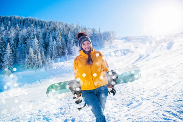 Deportiva hembra sostiene snowboard en montañas en jeans — Foto de Stock