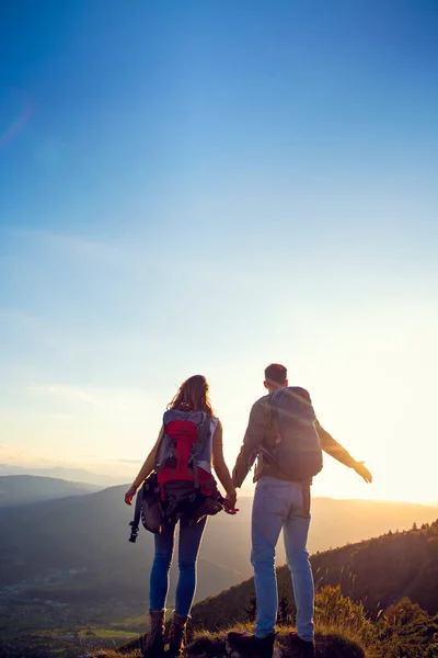 Senderistas con mochilas relajándose en la cima de una montaña y disfrutando de la vista del valle —  Fotos de Stock