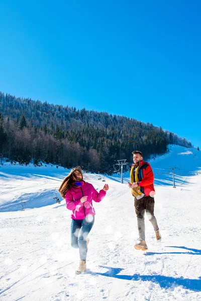 Luta de bolas de neve. Casal de inverno se divertindo jogando na neve ao ar livre. Jovem alegre feliz casal multi-racial . — Fotografia de Stock