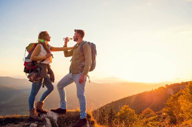 Genç çift dağın zirvesinde yürüyüş yapıyor içme suyu içiyor.