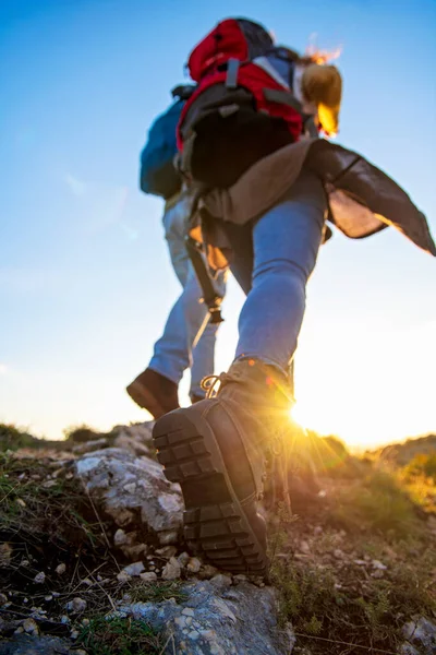 Tourist couple wearing hiking boots walk up a grassy hill in Alps. — Stock Photo, Image