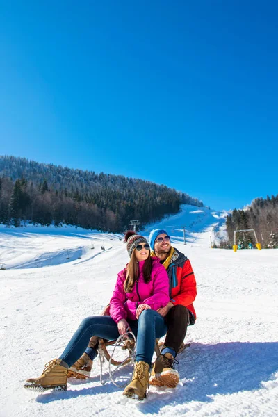 Joven pareja feliz trineo en invierno en el centro de esquí — Foto de Stock
