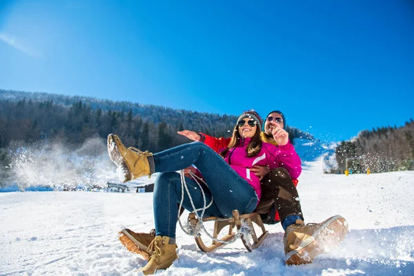 Joven pareja feliz trineo en invierno en el centro de esquí — Foto de Stock