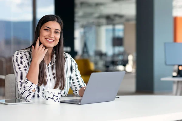 Glimlachende jonge zakenvrouw aan het werk in modern kantoor. — Stockfoto