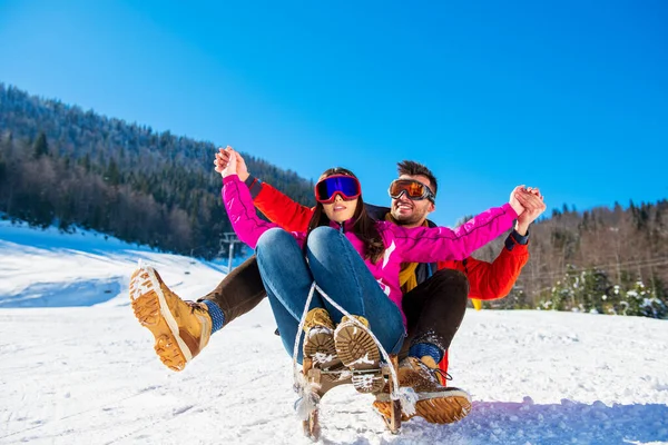 Joven feliz pareja en sledge tener divertido — Foto de Stock