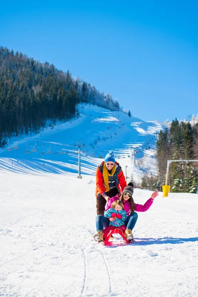 Familia feliz en nieve montando en trineo . — Foto de Stock