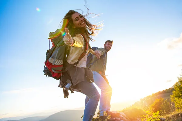 Mensen die elkaar helpen een berg te beklimmen bij zonsopgang. — Stockfoto
