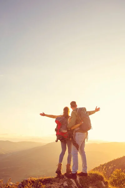 Hikers with backpacks relaxing on top of a mountain and enjoying the view of valley — Stock Photo, Image