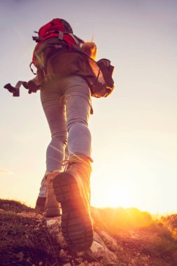 Yürüyüş botu giyen turist çift Alplerdeki çimenli bir tepede yürüyor..