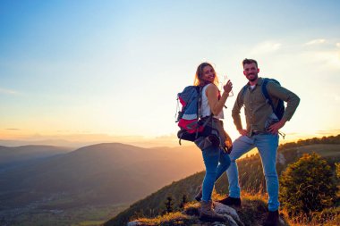 Genç çift dağın zirvesinde yürüyüş yapıyor içme suyu içiyor.