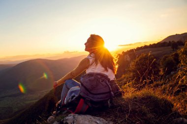 Genç kadın elini dağın tepesine kaldır ve gün batımında gökyüzü soyut arkaplan.