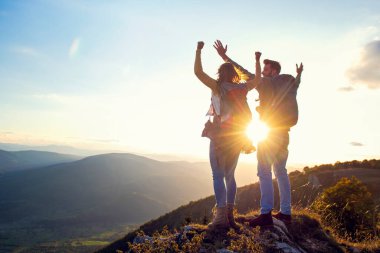 Mutlu çift, yaz yürüyüşü sırasında gün batımında dağın tepesinde gezen turist.