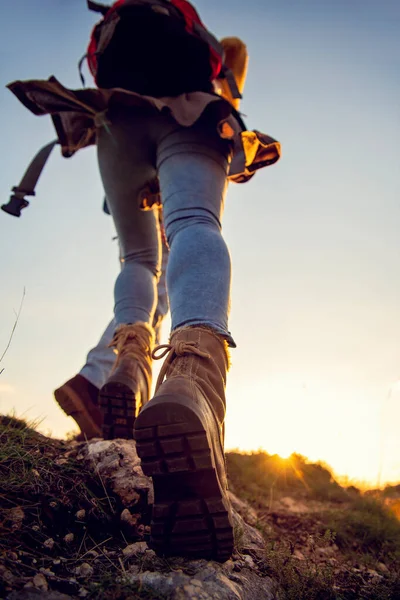 Tourist couple wearing hiking boots walk up a grassy hill in Alps. — Stock Photo, Image