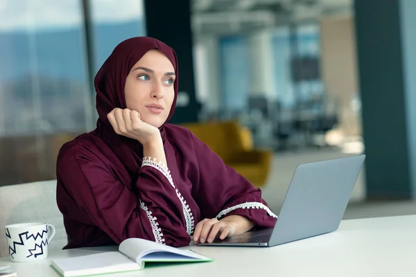 Pensive arabic businesswoman sitting at workplace in office